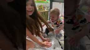 Toddler giggles uncontrollably as mom pops the packing bubbles