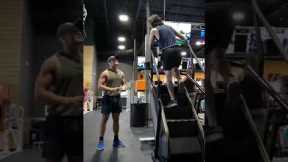 Two Guys Share a Stair Climber at Gym
