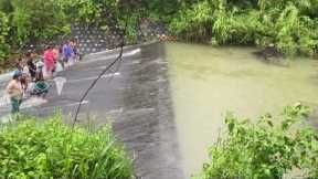 Locals go fishing in fast-flowing weir following heavy rain