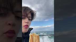Rogue wave splashes over railing and drenches woman snacking on baguette